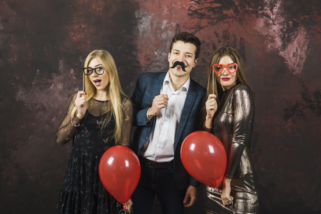 3 Personen mit Fotobox-Accessoires (Brillen, Bart) und Ballons. Hohe Auflösung, nicht verpixelt.